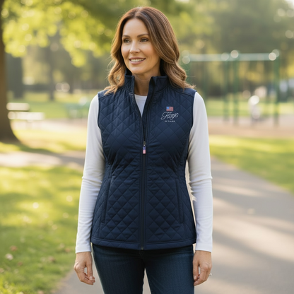 Woman wearing a navy quilted vest with Flags of Valor logo in a park setting