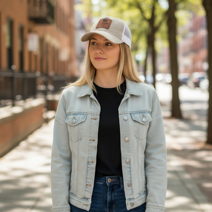 Woman wearing a light blue denim jacket and cap on a city street.